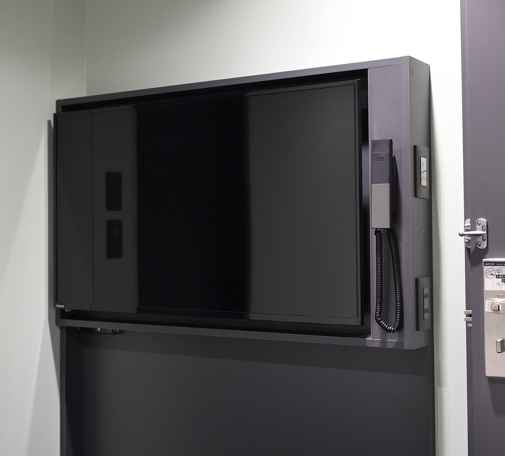 The large wall-mounted television creates enough space to move around the bed.