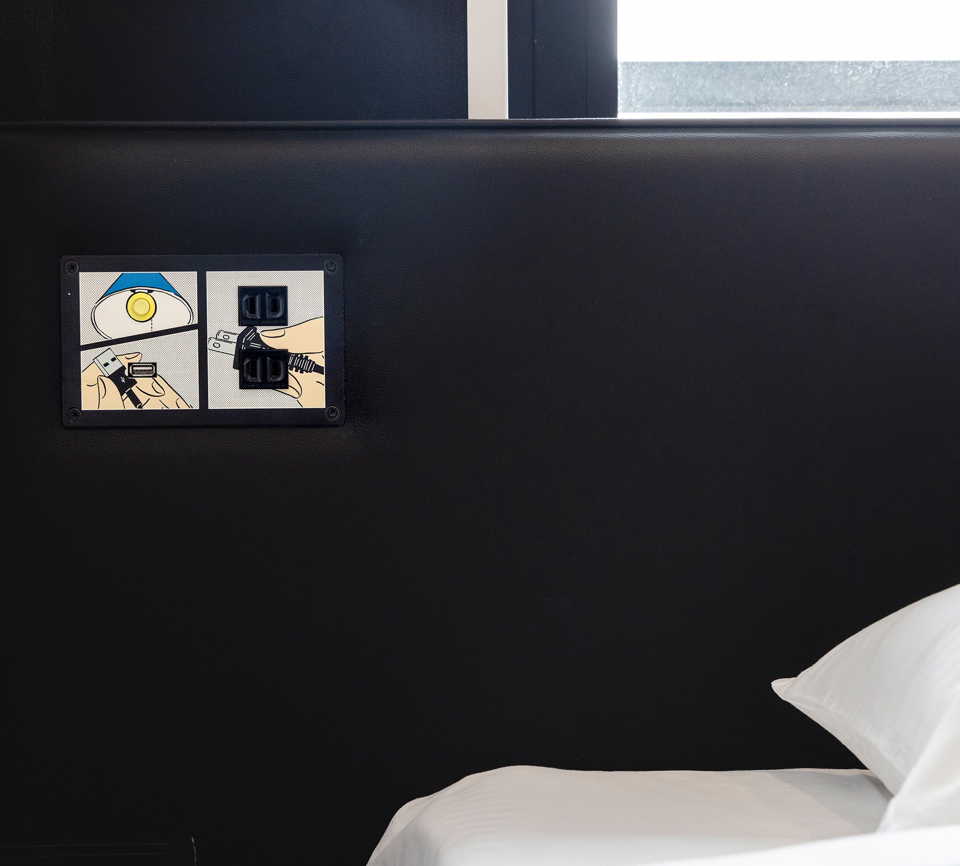A light switch, two electrical outlets, and one USB slot are available at the bedside.