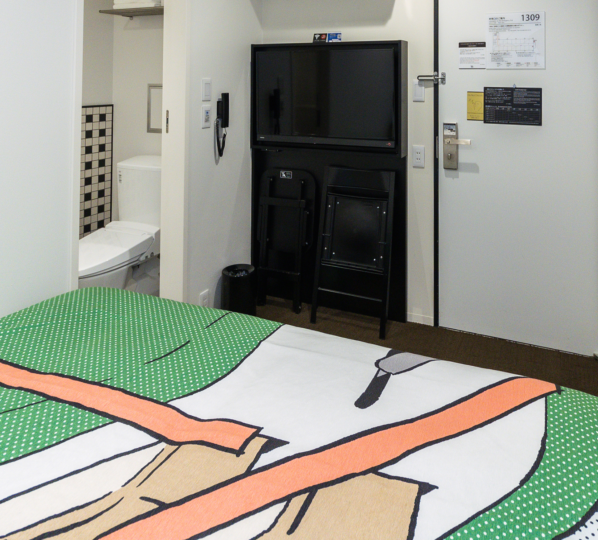 The room has a large wall-mounted television. Enjoy a relaxing space, while leisurely unwinding on the bed.