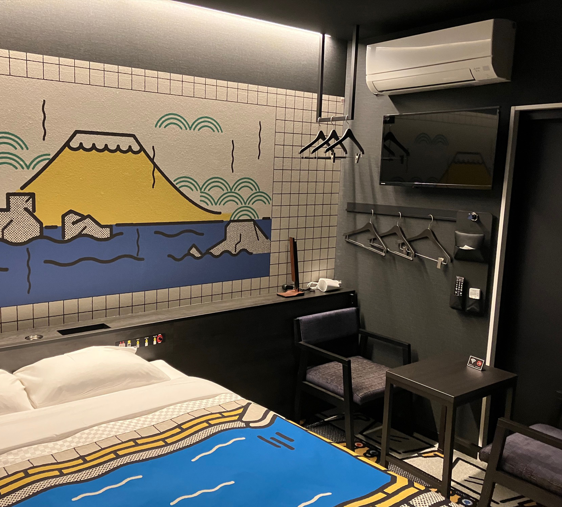 객실 내에 테이블, 의자, 에어컨, 옷걸이가 배치되어 있습니다.